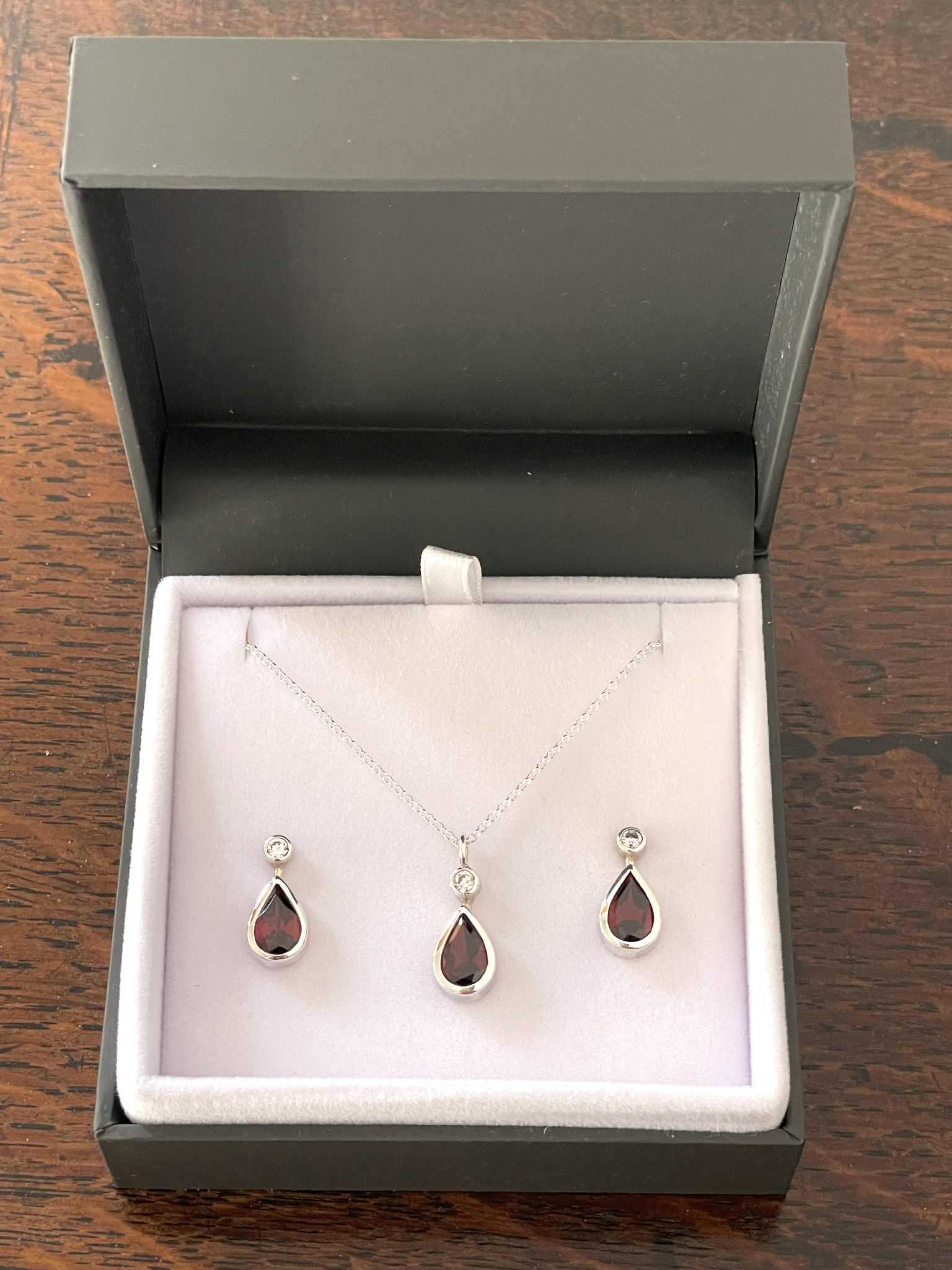 The garnet earring and pendant together in a display box
